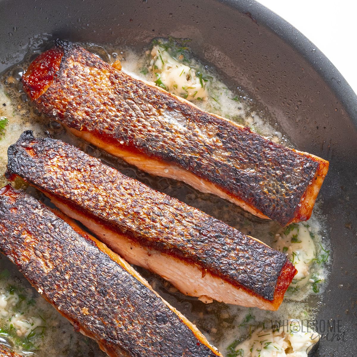 Pan seared salmon in skillet.